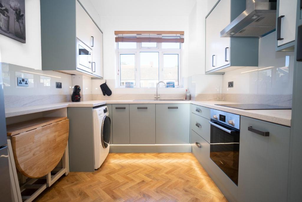 a kitchen with white cabinets and a sink and a dishwasher at Amazing Apt with 2 bathrooms close to Battersea Park in London