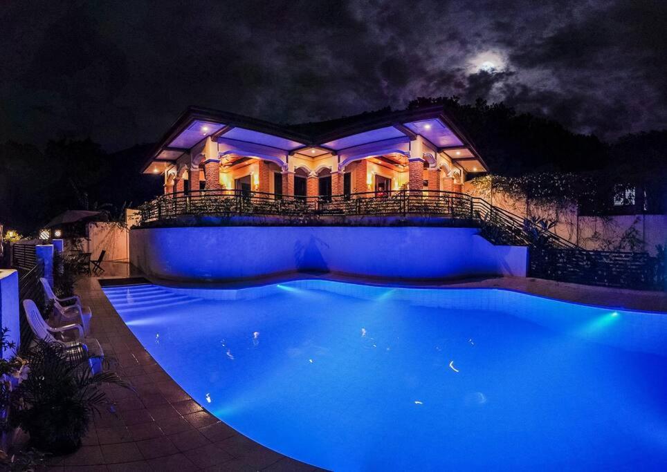 a large house with a blue pool at night at Twin House Villa in Coron