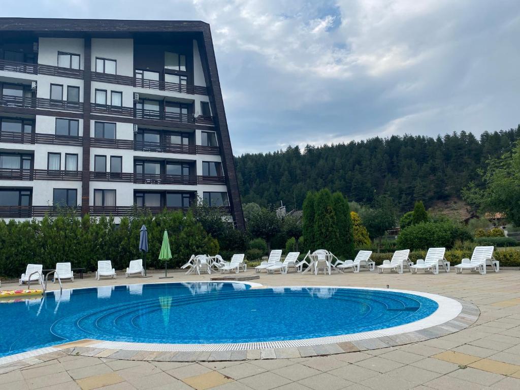 un hotel con piscina y sillas y un edificio en Cosy studios with mountain view near Bansko, en Razlog