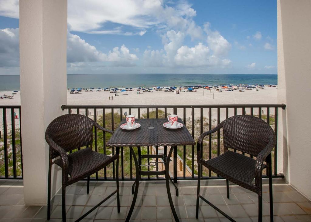 a table and chairs on a balcony with a view of the beach at The Palms 313A in Orange Beach
