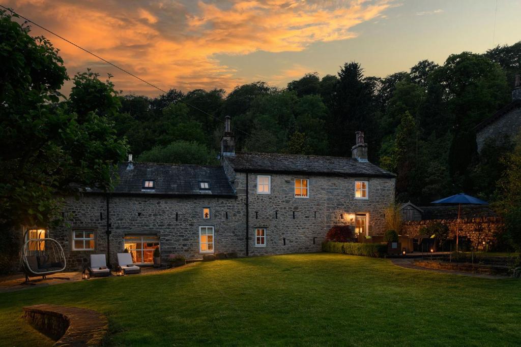an old stone house with a large yard at sunset at Carrholme Cottage in Settle