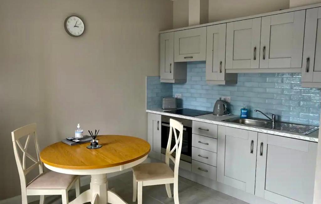 a kitchen with a table and chairs and a clock at Erne Getaway No.5 Brand new 1 bed apartment in Enniskillen