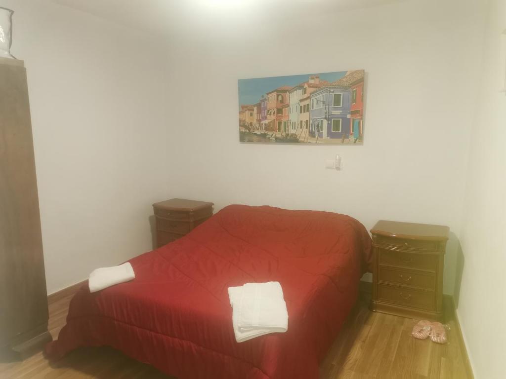 Un dormitorio con una cama roja y una pintura en la pared en casa luna cuesta del rio 15, en Valdeganga
