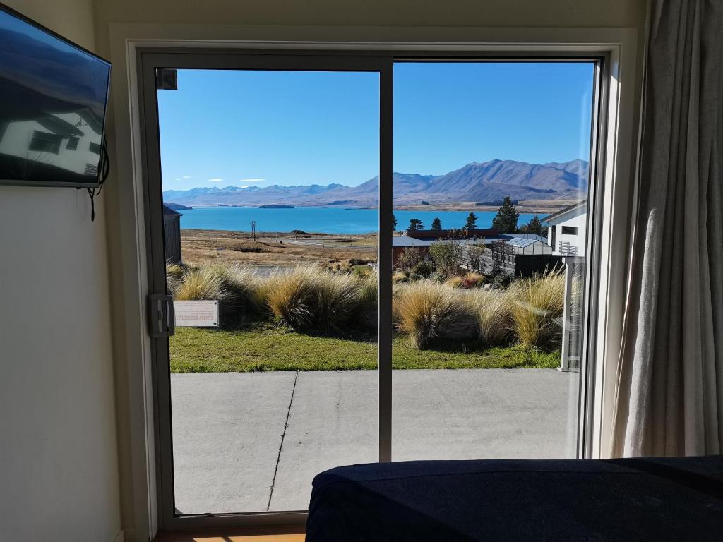 a sliding glass door with a view of a lake at Antair Lakeview Lodge in Lake Tekapo