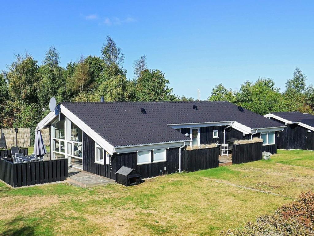 a black house with a fence in a yard at 8 person holiday home in Otterup in Otterup