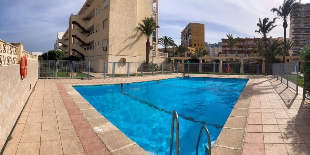 濱海羅克塔斯的住宿－Apartamento Las Chumberas，一座大型蓝色游泳池,位于大楼旁边