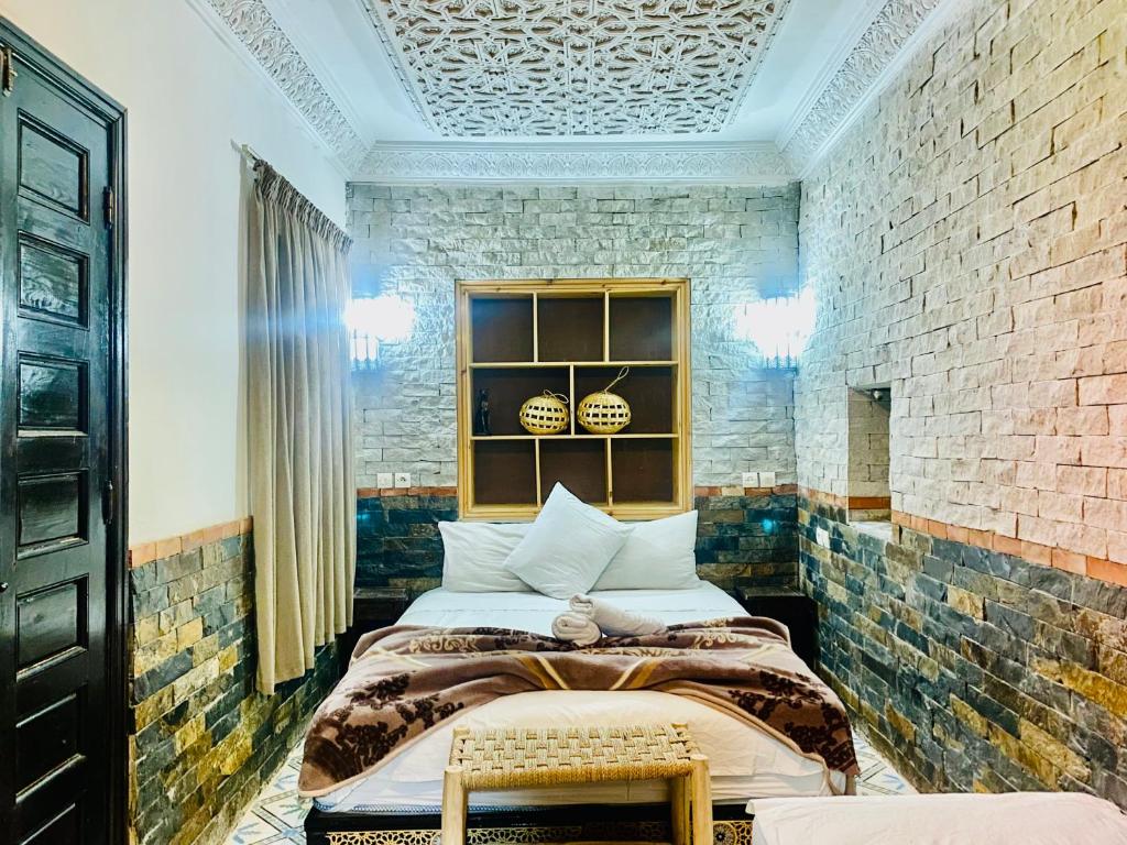 - une chambre avec 2 lits et un mur en briques dans l'établissement Riad 46, à Marrakech