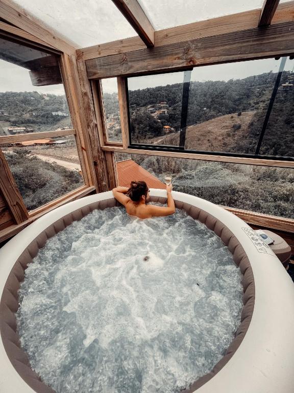 a woman sitting in a jacuzzi tub in a house at Pousada Vale da Magia in Praia do Rosa