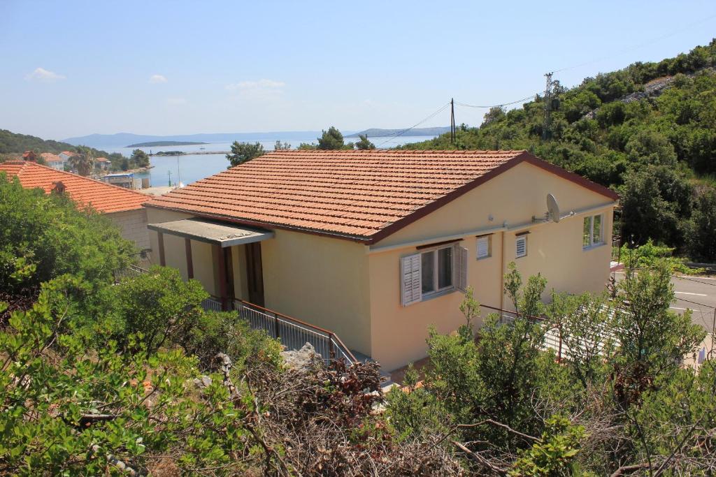 ein gelbes Haus mit rotem Dach auf einem Hügel in der Unterkunft Apartments by the sea Zaglav, Dugi otok - 8145 in Zaglav