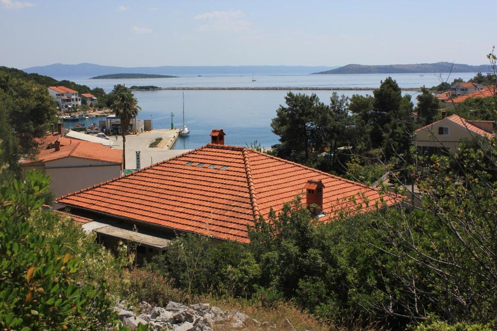 ein orangenes Dach auf einem Haus mit dem Ozean im Hintergrund in der Unterkunft Apartments by the sea Zaglav, Dugi otok - 8146 in Zaglav