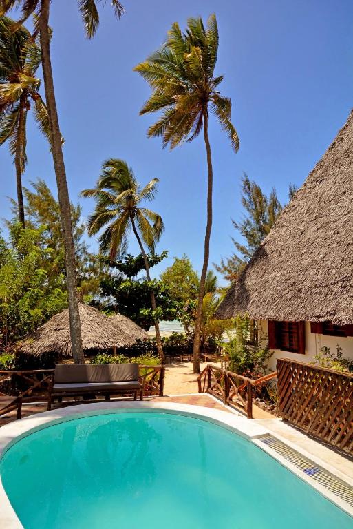 a swimming pool at a resort with palm trees at Kipepeo Lodge Zanzibar in Jambiani