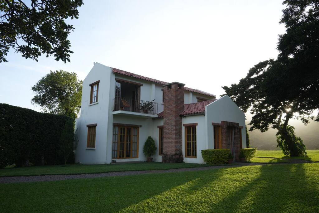 a large white house with a grass yard at 5TO PISO by Bourbon Hostal in Juayúa