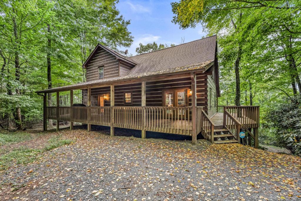 une cabane en rondins dans les bois avec une grande terrasse dans l'établissement Rustic Retreat, à West Jefferson