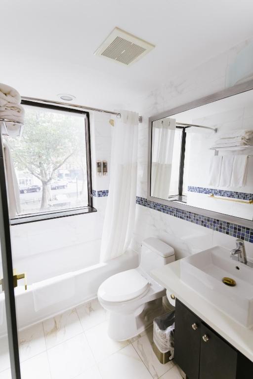 a bathroom with a toilet and a sink and a mirror at Hotel Richland LES in New York