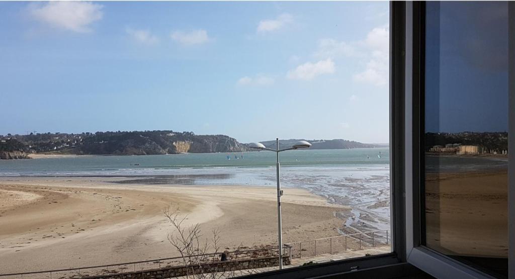 una finestra con vista su una spiaggia e un lampione di Chez Nany, chaleureux duplex sur le port de Morgat a Crozon