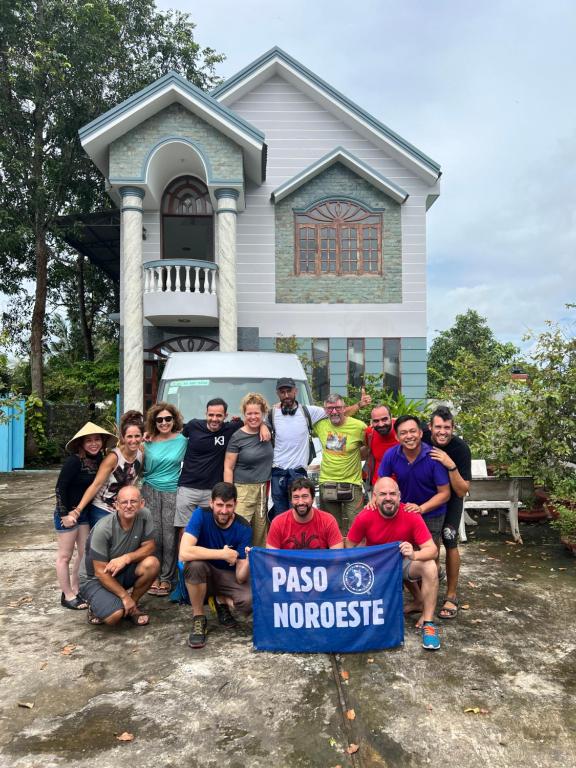 a group of people posing in front of a house at Sao Mai Hotel in Cai Be