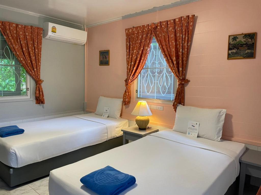 two beds in a room with a window at Phuket Golden Sand Inn - SHA Extra Plus in Karon Beach