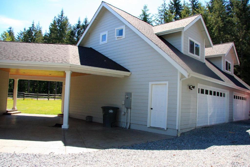 uma casa branca com uma garagem e uma entrada em The Loft At The Nisqually Highland Ranch em Eatonville