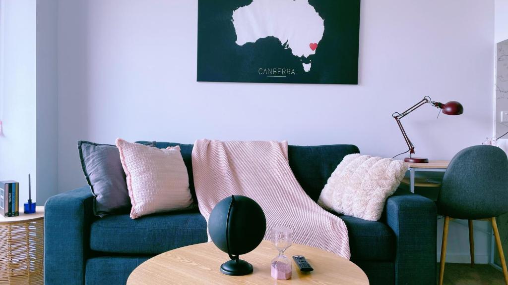 a living room with a blue couch and a table at Brand New PARK AVENUE Apartment in the Heart of Canberra City in Canberra