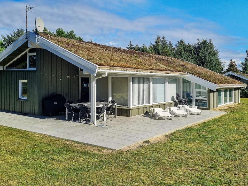 une maison verte avec une terrasse dotée d'une table et de chaises dans l'établissement 12 person holiday home in Saltum, à Saltum