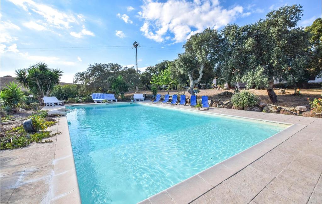 una piscina con sillas azules y árboles en Cozy Home In Sedini With Wifi, en Sedini