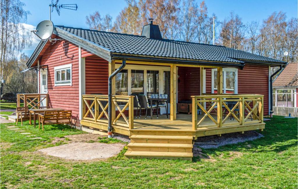 a small red house with a large wooden deck at Nice Home In Ödeshög With Wifi in Ödeshög