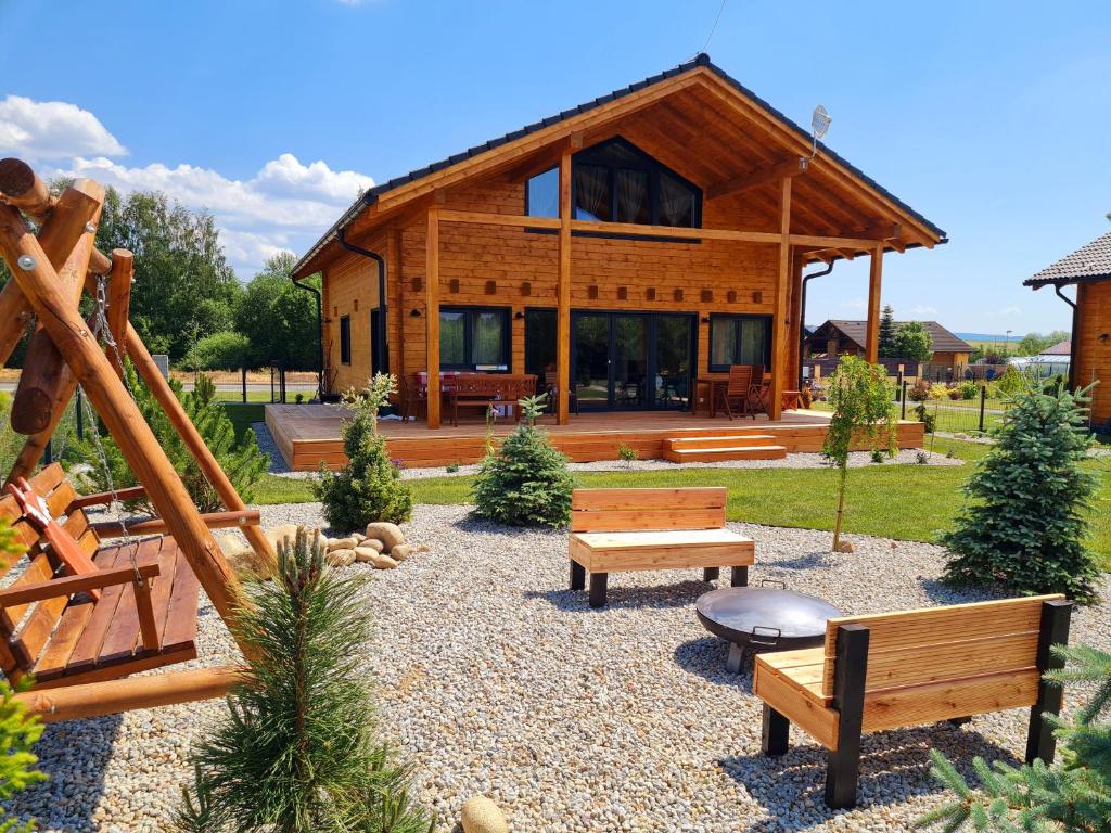 une cabane en rondins avec bancs devant elle dans l'établissement Panorama Tatry Chalets, à Veľká Lomnica