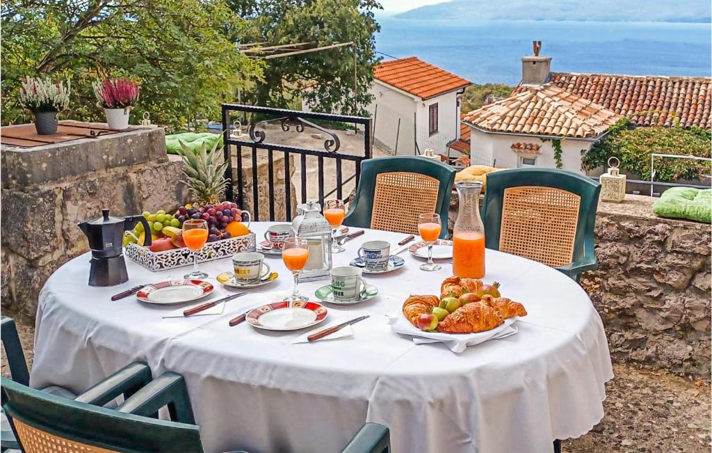 einen Tisch mit einem weißen Tischtuch und Obst darauf. in der Unterkunft Nice Home In Dragozetici With House Sea View in Dragozetići
