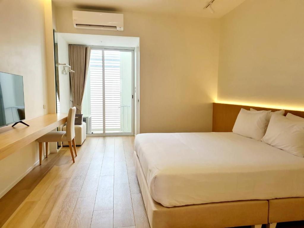 Habitación de hotel con cama, escritorio y ventana en WIIN Phetchaburi วิน เพชรบุรี, en Phetchaburi