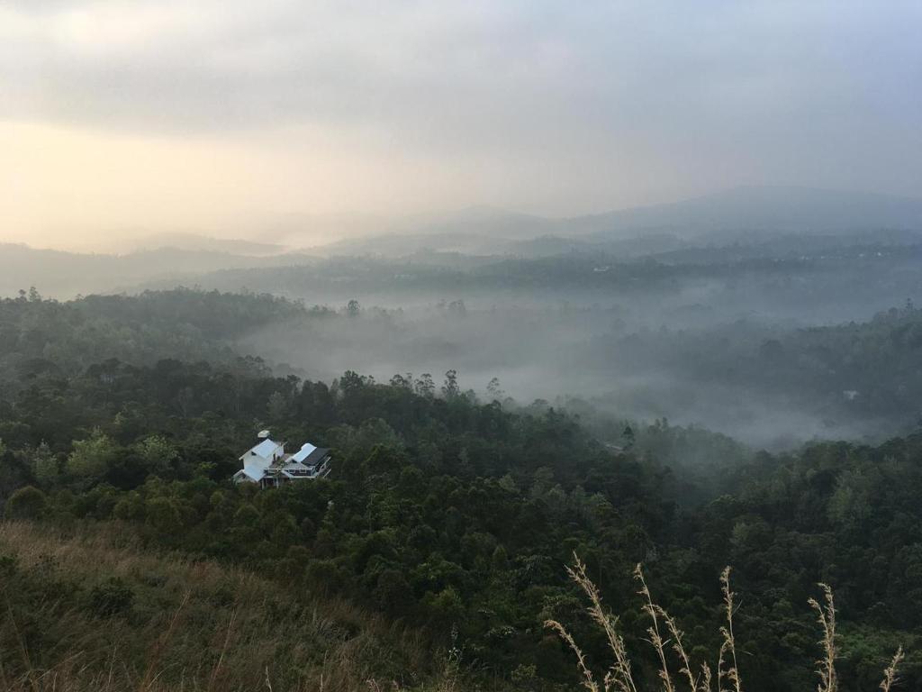 une personne assise au sommet d'une colline surplombant une forêt dans l'établissement Titha Service Villa, à Santhanpara