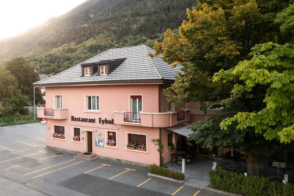 een groot roze gebouw op een parkeerplaats bij Hotel-Restaurant Eyholz in Visp