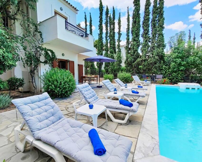 a group of lounge chairs next to a swimming pool at Villa Nova s.r Sea View in Porto Heli