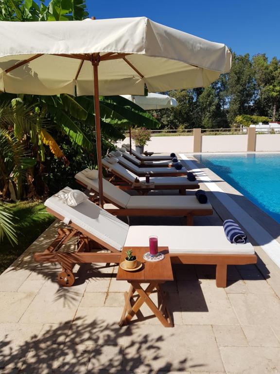 a group of lounge chairs and an umbrella next to a pool at Villa Bade in Dalyan