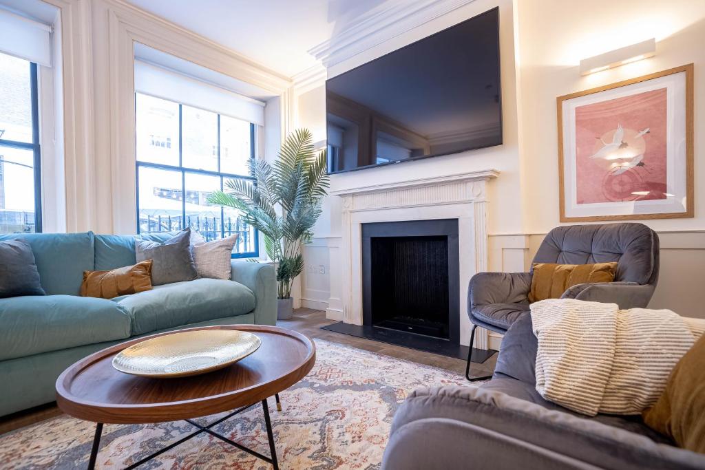 a living room with couches and a fireplace at Stylish & Spacious 3Bed Home near Liverpool Street Train Station by Belvilla in London