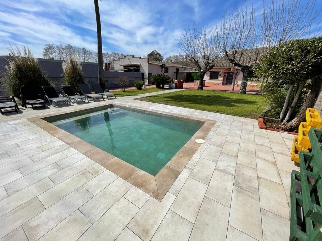 a swimming pool in a yard with a patio at Molí den burch in Santa Eulalia de Ronsaná