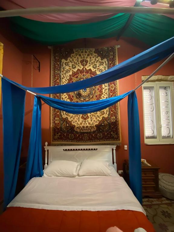 a bed with a canopy with blue drapes at Hollywood Inn Palermo in Palermo