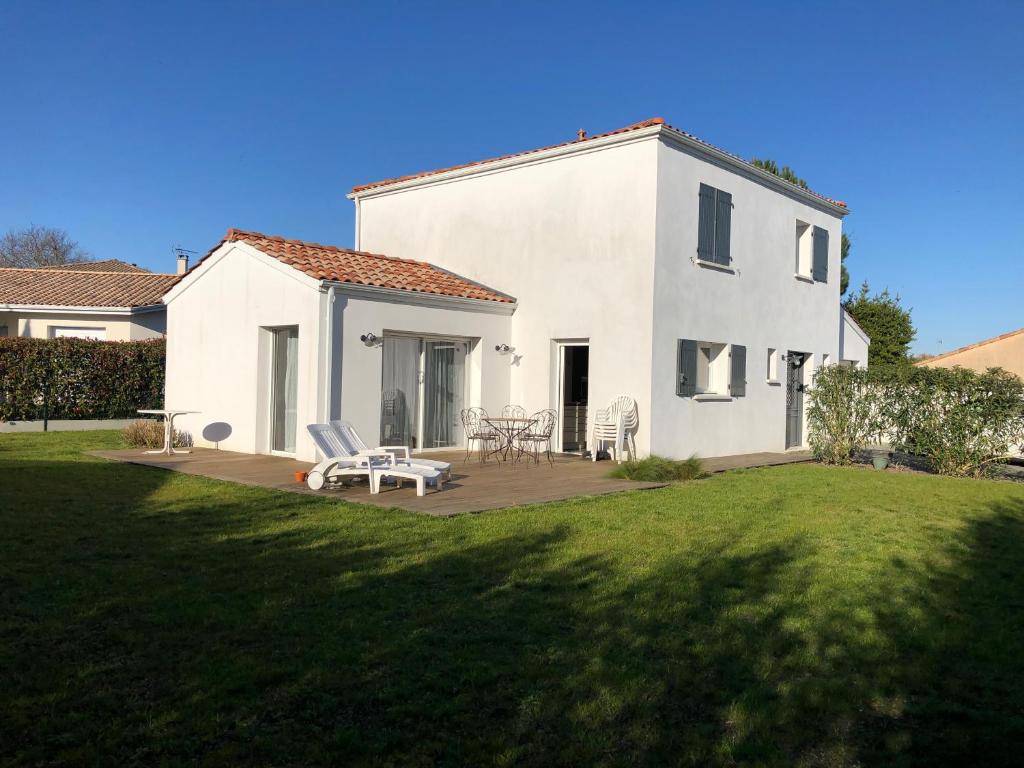 a white house with a patio and a lawn at Charmante maison à proximité de Bordeaux in Gradignan