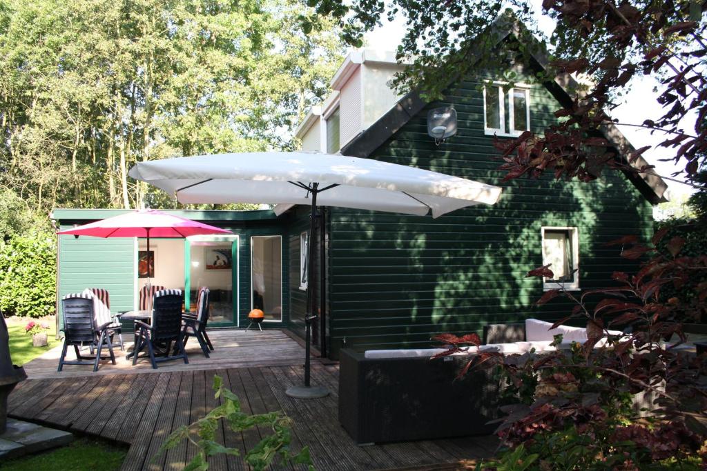 un patio con sombrilla, mesa y sillas en Holiday Home De Zuwe - Loosdrecht, en Kortenhoef