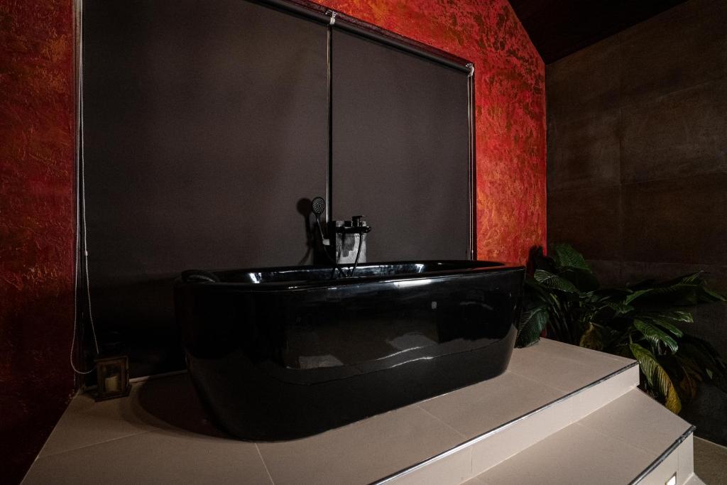 a black tub in a bathroom with a red wall at The Edgware Cabana in Nuwara Eliya