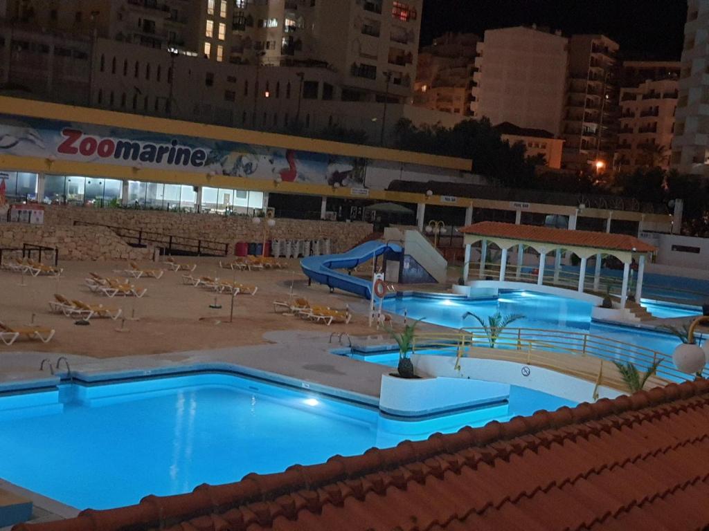 een groot zwembad in een stad 's nachts bij Portimão Appartement clube praia da rocha in Portimão