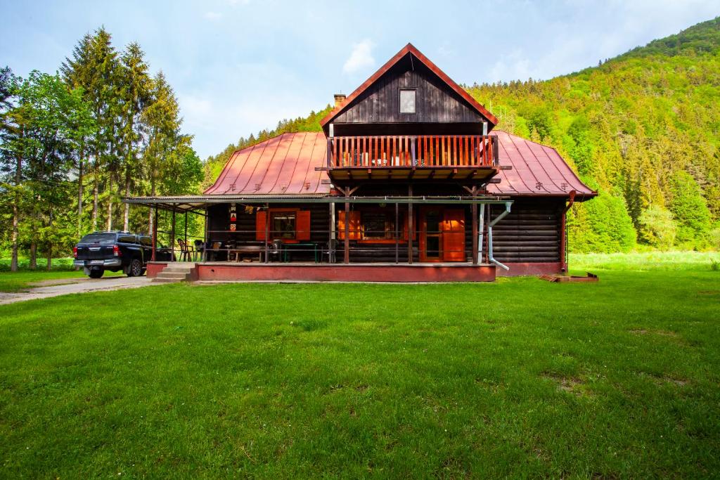 a large house with a red roof on a green field at Chata Smiech in Ružomberok