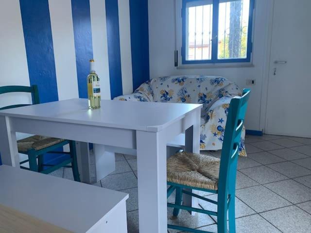 einen weißen Tisch mit einer Flasche Wein und einem Stuhl in der Unterkunft casa in riva al lago Diletta Spiti in Castelletto sopra Ticino