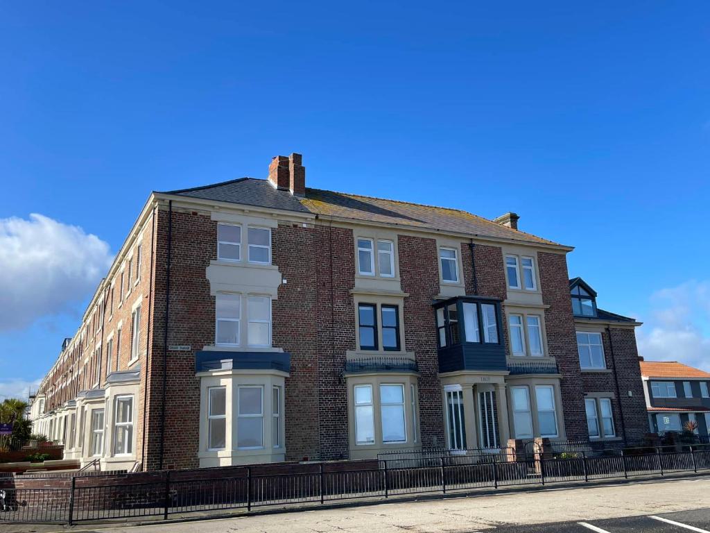 a brick building with white windows on a street at The Beach Front Apartment, Amazing Frontline Sea Views in Tynemouth