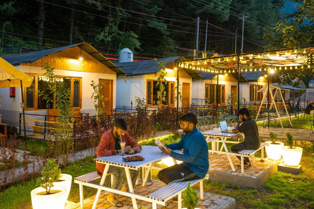 a group of people sitting at tables outside a house at The Hosteller Kasol, Riverside in Kasol
