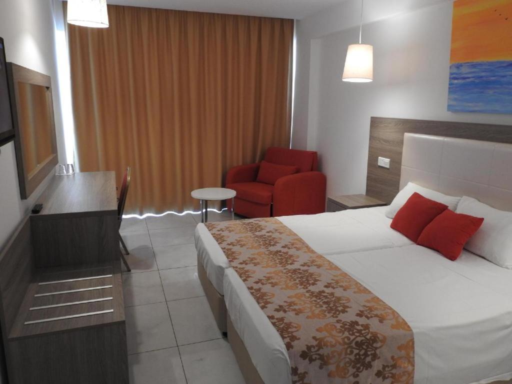 a hotel room with a bed and a chair at Corfu Hotel in Ayia Napa