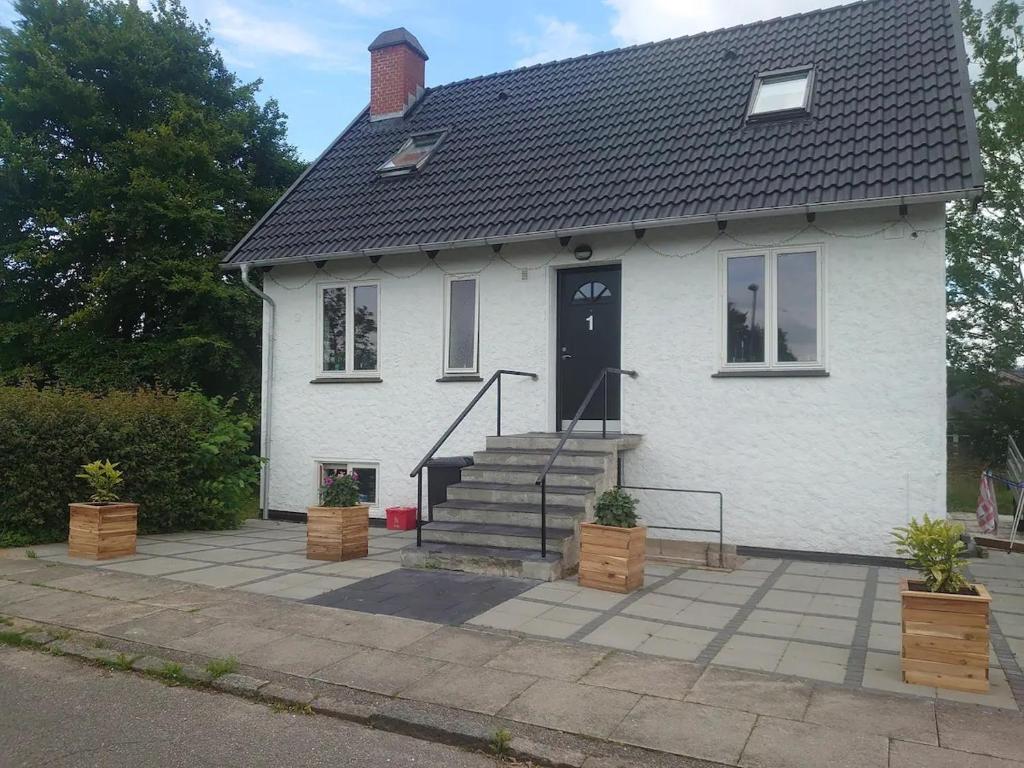 Biały dom z czarnymi drzwiami i schodami w obiekcie Byhus Vejle w mieście Vejle