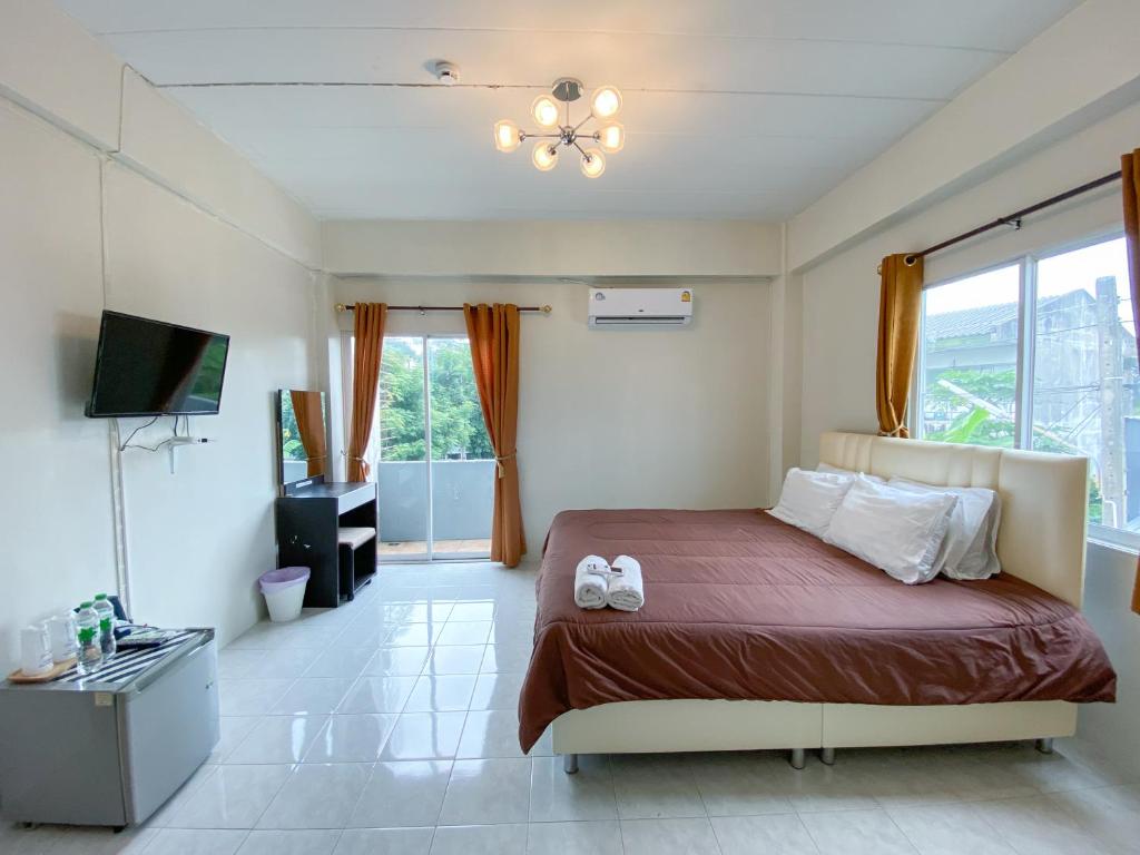 a bedroom with a bed and a television in it at Uh Hostel in Bangsaen