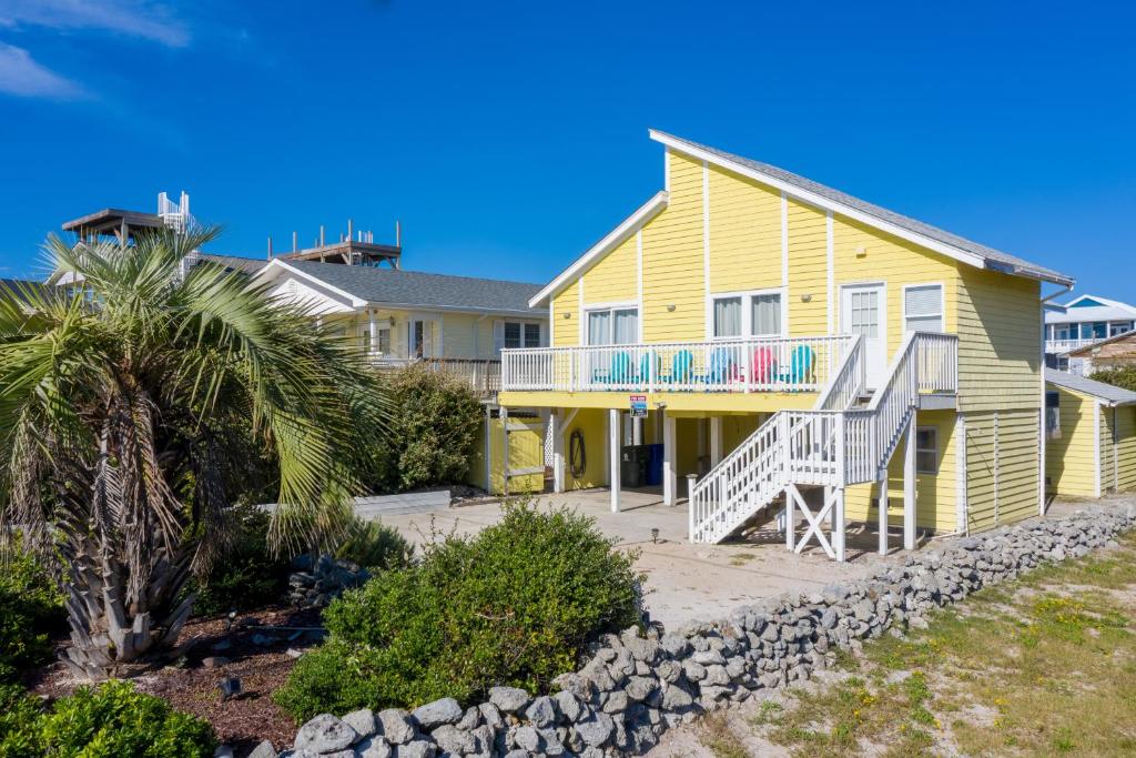 a yellow house with a palm tree in front of it at Living the Dream in Surf City