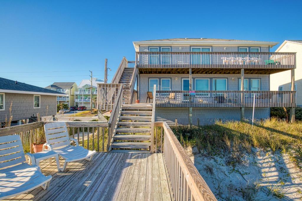 een huis met een terras en twee stoelen op een strand bij Chambless at Ease in Surf City