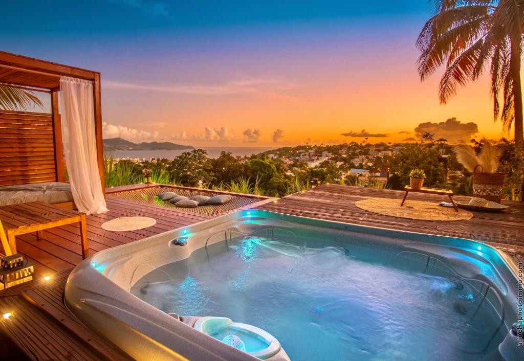 a hot tub on a deck with a sunset in the background at Créole Bay - Suites and Spa in Fort-de-France